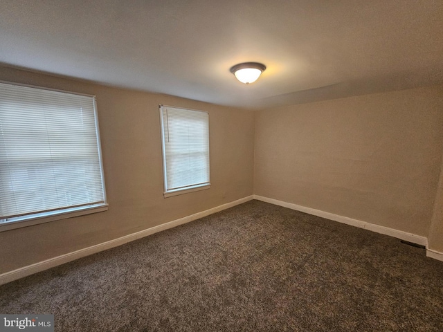 unfurnished room featuring dark colored carpet