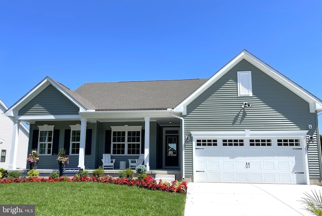 view of front facade featuring a porch, a garage, and a front lawn