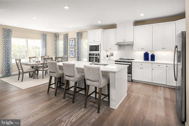 kitchen featuring white cabinetry, a center island with sink, stainless steel appliances, and dark hardwood / wood-style floors