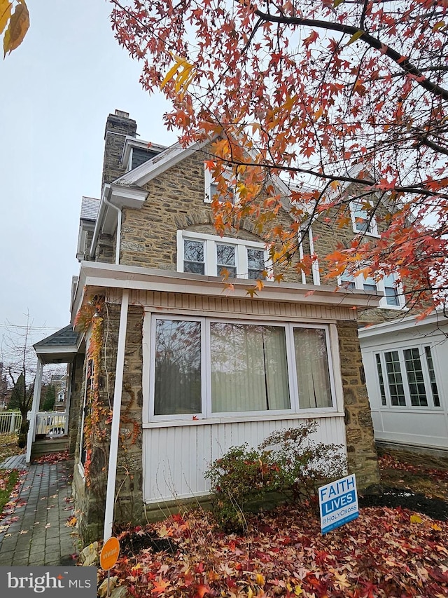 view of side of home featuring stone siding and a chimney