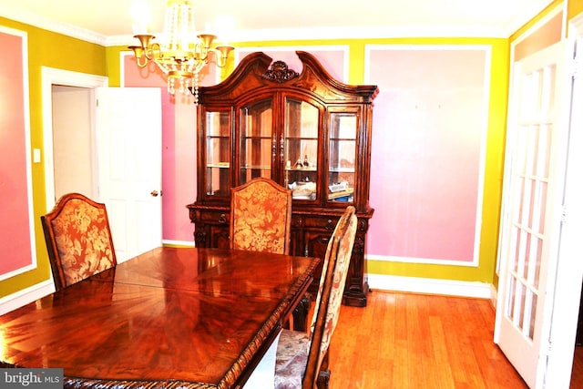 dining area with ornamental molding, wood finished floors, baseboards, and a chandelier