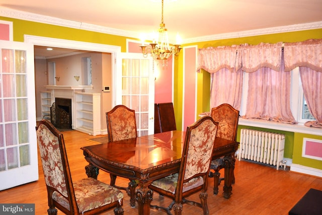 dining area with ornamental molding, radiator, wood finished floors, and a chandelier