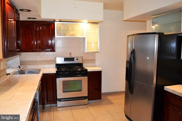 kitchen featuring stainless steel gas range oven, fridge with ice dispenser, backsplash, and tile counters