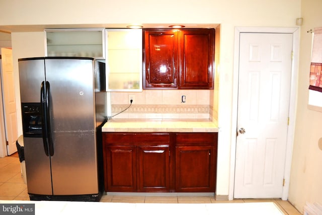 kitchen with light countertops, light tile patterned floors, stainless steel fridge with ice dispenser, and reddish brown cabinets