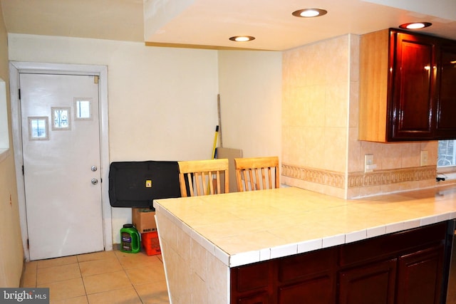 kitchen featuring backsplash, recessed lighting, tile countertops, light tile patterned floors, and dark brown cabinets