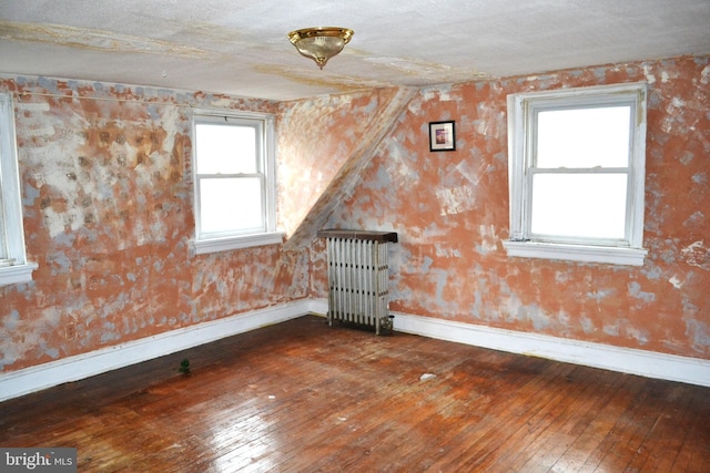 empty room featuring hardwood / wood-style floors, radiator, and baseboards