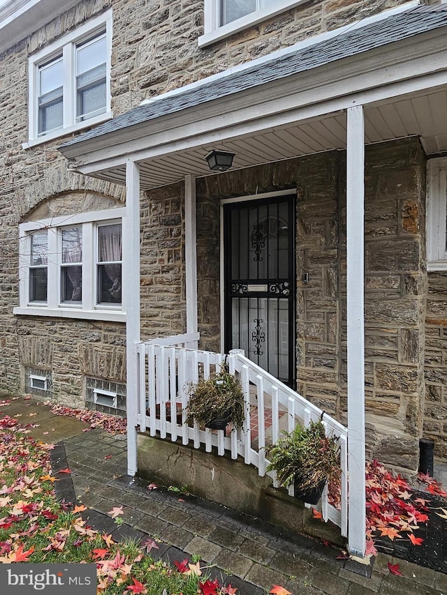 doorway to property with stone siding and a porch