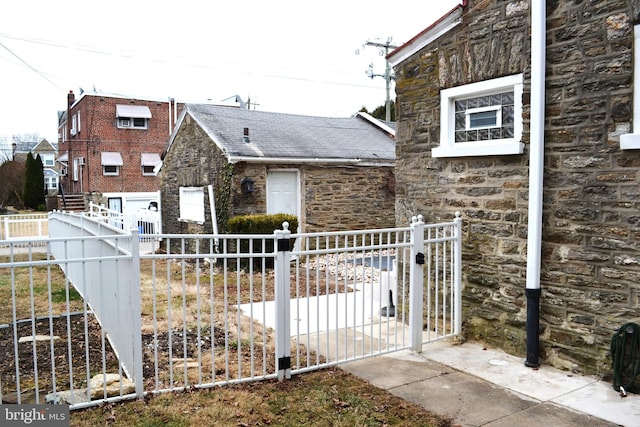 view of side of property with stone siding, fence private yard, and a gate