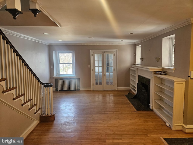 living room with light wood finished floors, radiator, crown molding, stairway, and a fireplace with flush hearth