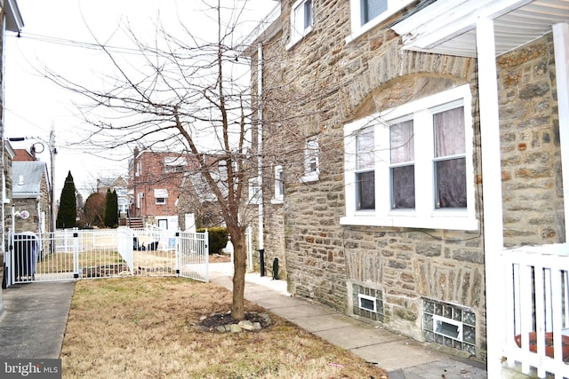 view of side of property with stone siding and fence