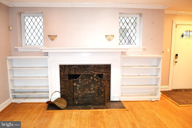 interior details featuring a fireplace with flush hearth, wood finished floors, baseboards, and ornamental molding