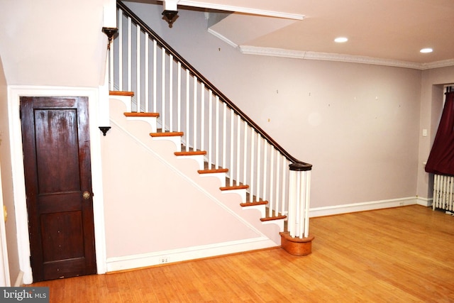 stairway with baseboards, radiator heating unit, ornamental molding, recessed lighting, and wood finished floors