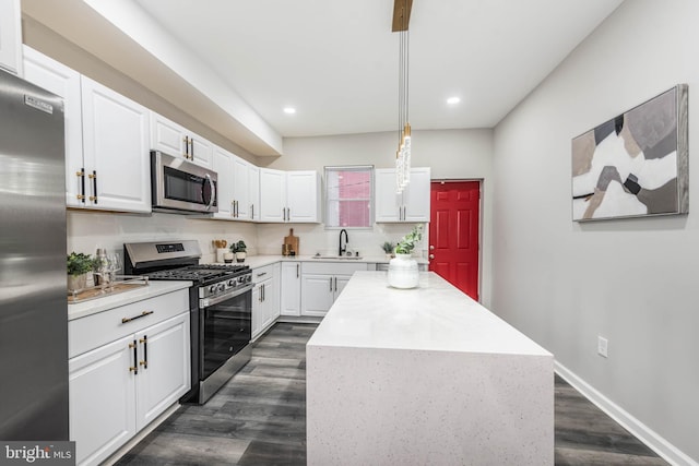 kitchen featuring pendant lighting, sink, a kitchen island, white cabinetry, and stainless steel appliances