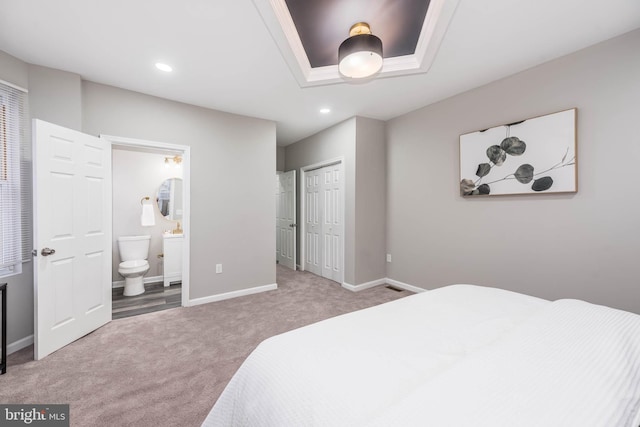 bedroom featuring connected bathroom, light colored carpet, and a closet