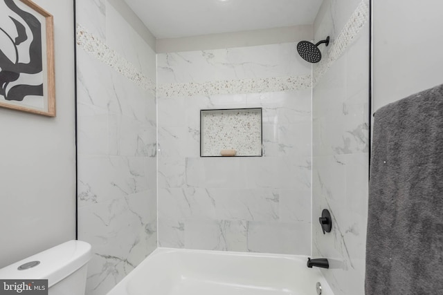 bathroom featuring tiled shower / bath combo and toilet