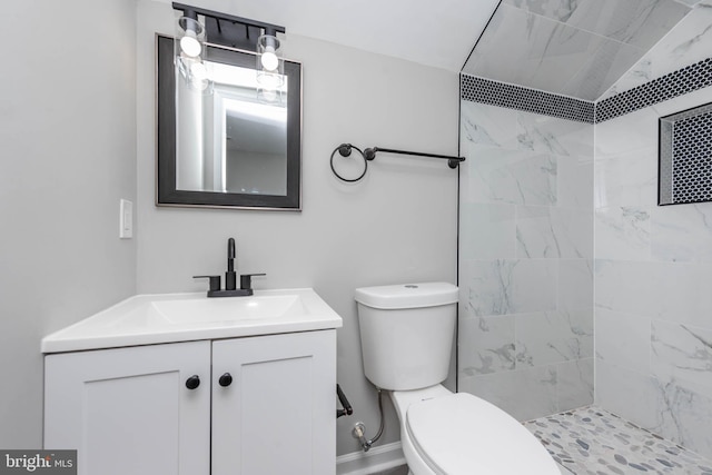 bathroom with tiled shower, vanity, toilet, and vaulted ceiling