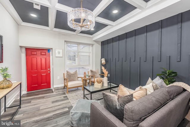 living room with ornamental molding, a chandelier, coffered ceiling, and hardwood / wood-style flooring