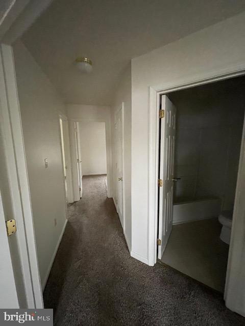 hall with dark colored carpet