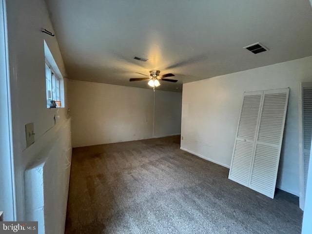 unfurnished bedroom with ceiling fan and dark colored carpet