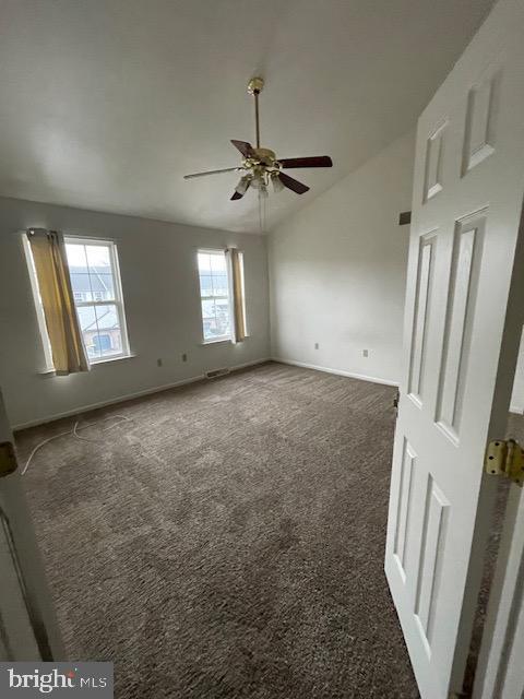 carpeted spare room with ceiling fan and vaulted ceiling