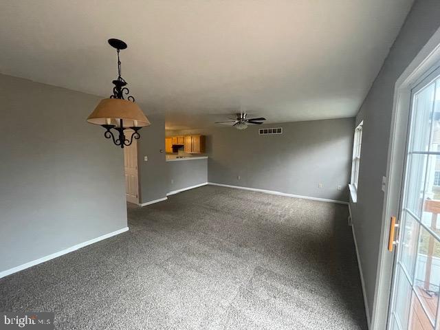 unfurnished living room featuring dark carpet and ceiling fan