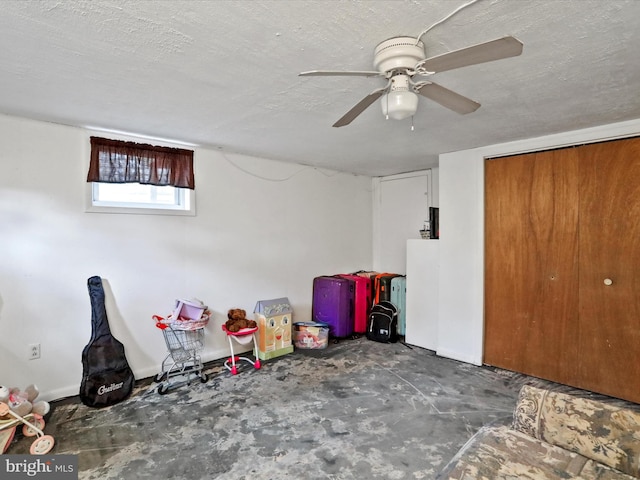 basement featuring ceiling fan and a textured ceiling