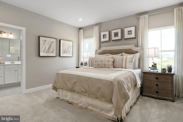 bedroom with light colored carpet, sink, and connected bathroom