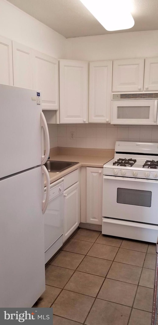 kitchen with decorative backsplash, white appliances, sink, white cabinets, and tile patterned flooring