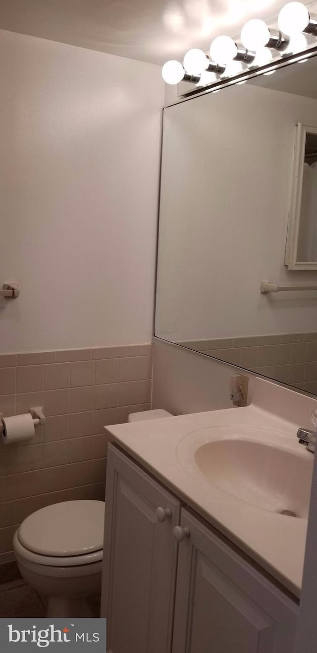 bathroom featuring vanity, tile walls, and toilet