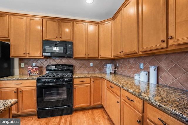 kitchen with black appliances, light hardwood / wood-style floors, backsplash, and stone counters