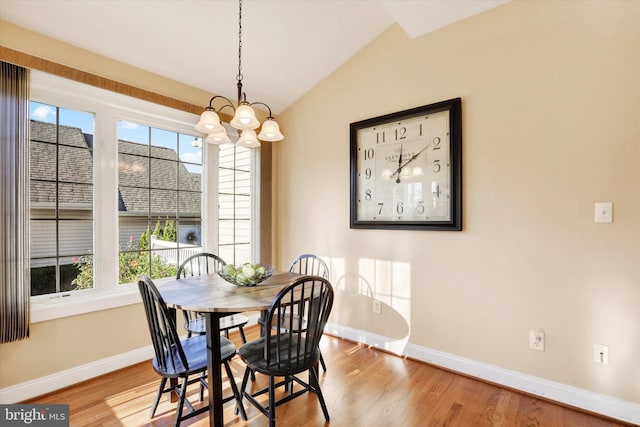 dining room with light wood-type flooring, vaulted ceiling, plenty of natural light, and a notable chandelier