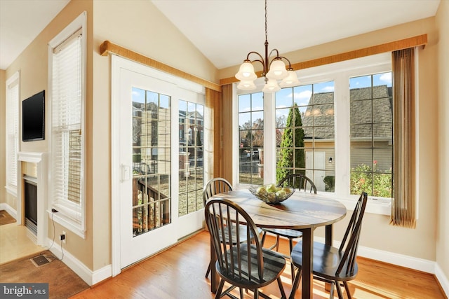 sunroom featuring plenty of natural light, lofted ceiling, a fireplace, and an inviting chandelier