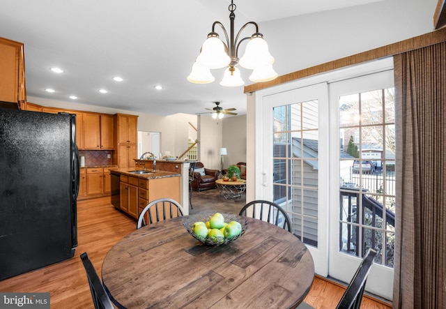 dining space featuring ceiling fan with notable chandelier, light hardwood / wood-style floors, and sink