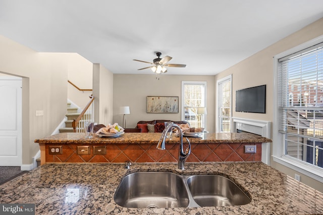 kitchen with dark stone countertops, ceiling fan, and sink