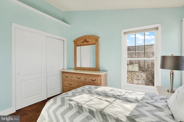 bedroom featuring dark colored carpet, vaulted ceiling, and a closet