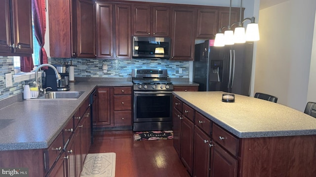 kitchen featuring appliances with stainless steel finishes, a breakfast bar, sink, backsplash, and dark hardwood / wood-style flooring