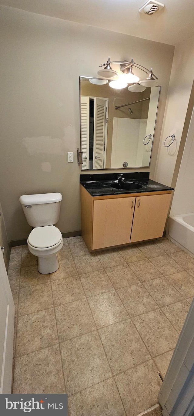 bathroom featuring a washtub, vanity, and toilet