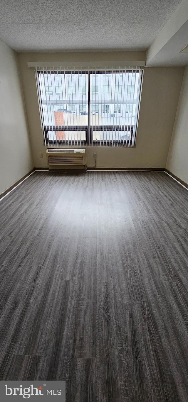 spare room with a healthy amount of sunlight, a textured ceiling, and hardwood / wood-style flooring