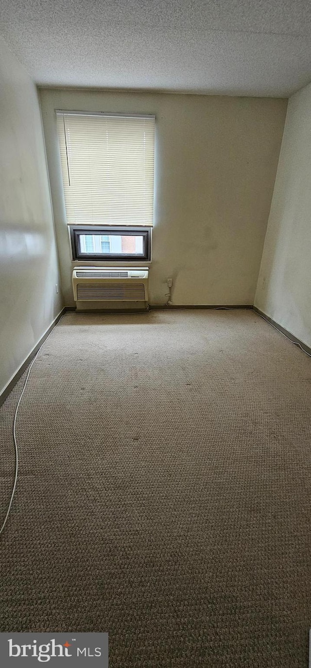 carpeted empty room featuring a textured ceiling