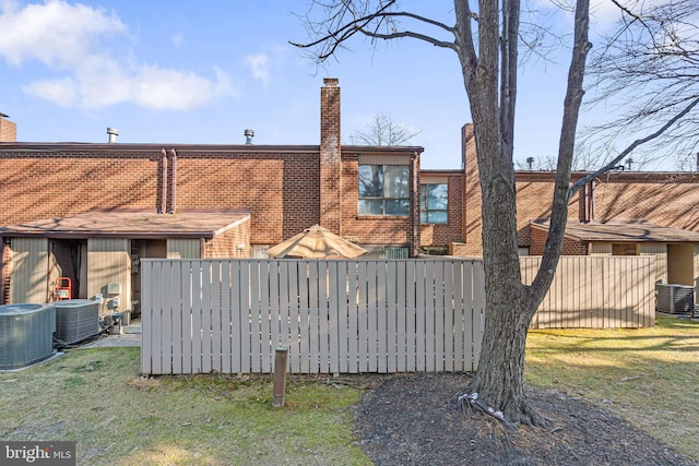 rear view of house featuring a lawn and central air condition unit