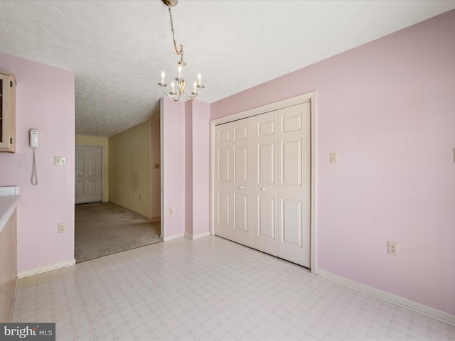 unfurnished room featuring a textured ceiling and a chandelier