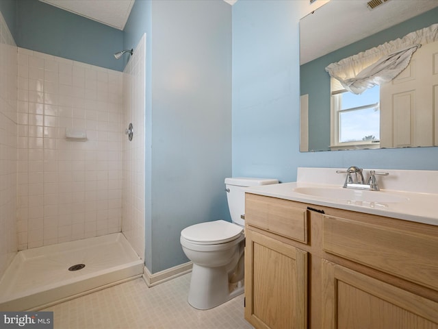 bathroom featuring vanity, tiled shower, and toilet