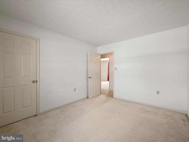 unfurnished room featuring light colored carpet and a textured ceiling