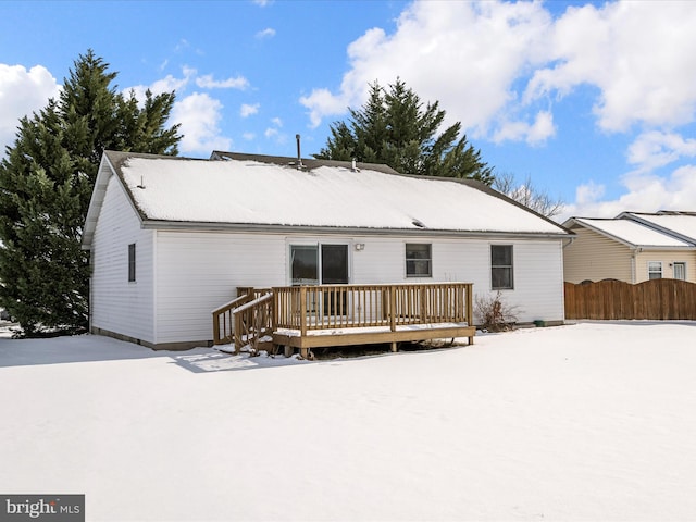 snow covered back of property featuring a deck