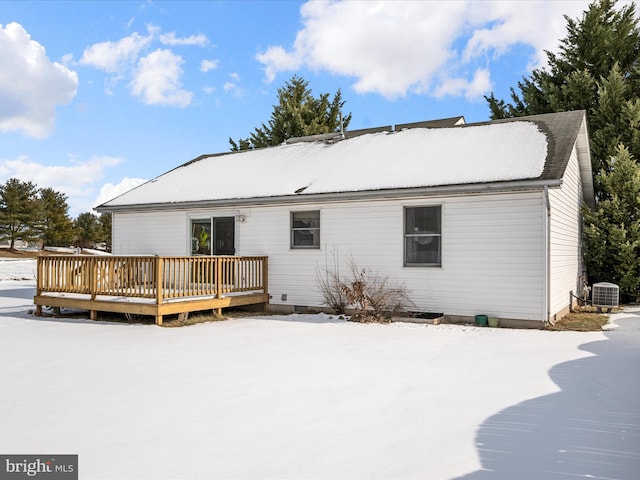 snow covered rear of property with central AC and a deck