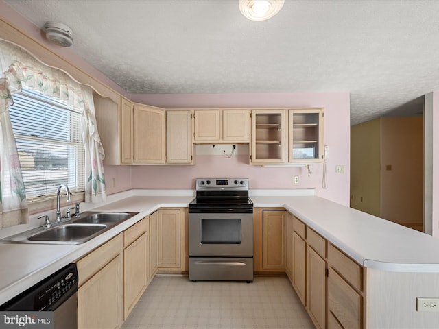 kitchen with appliances with stainless steel finishes, kitchen peninsula, sink, and light brown cabinets