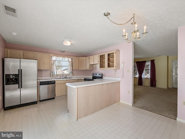 kitchen with appliances with stainless steel finishes, light brown cabinetry, decorative light fixtures, sink, and kitchen peninsula