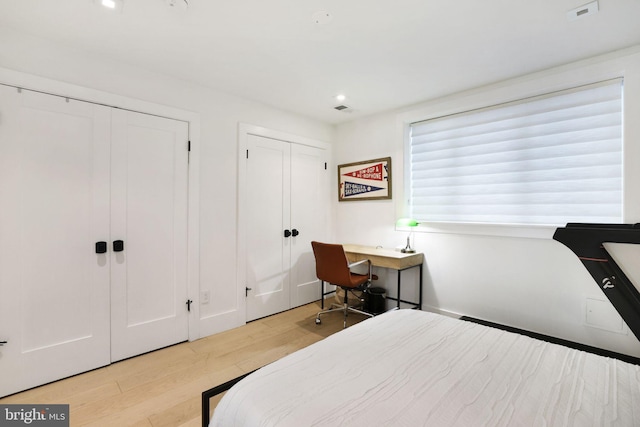 bedroom with two closets and light wood-type flooring