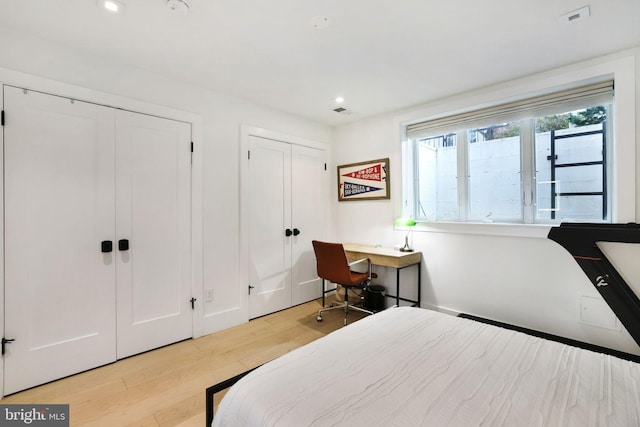 bedroom featuring two closets and light hardwood / wood-style floors