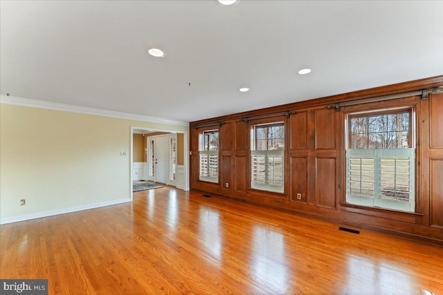 empty room with ornamental molding and light hardwood / wood-style flooring